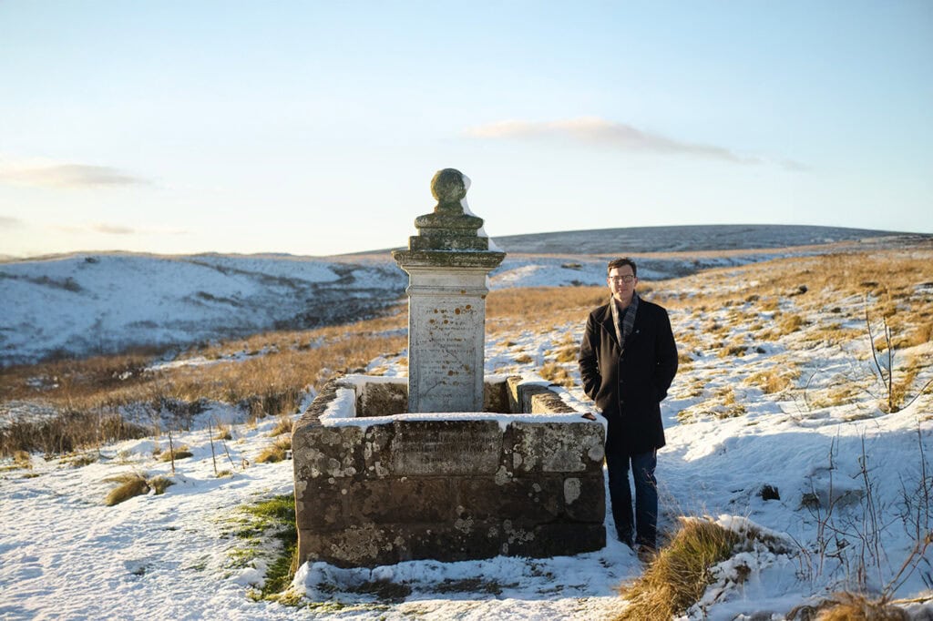 Presenter standing next to the John Brown memorial near Muirkirk. 
